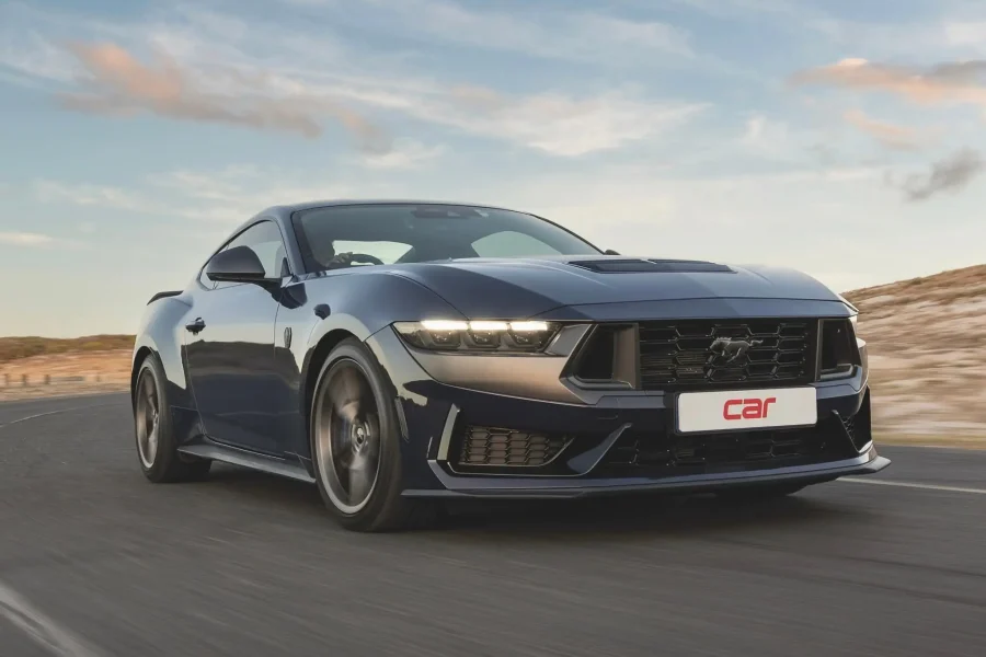 Dark blue Ford Mustang driving quickly on a coastal road for the About section of Old School Detailing.